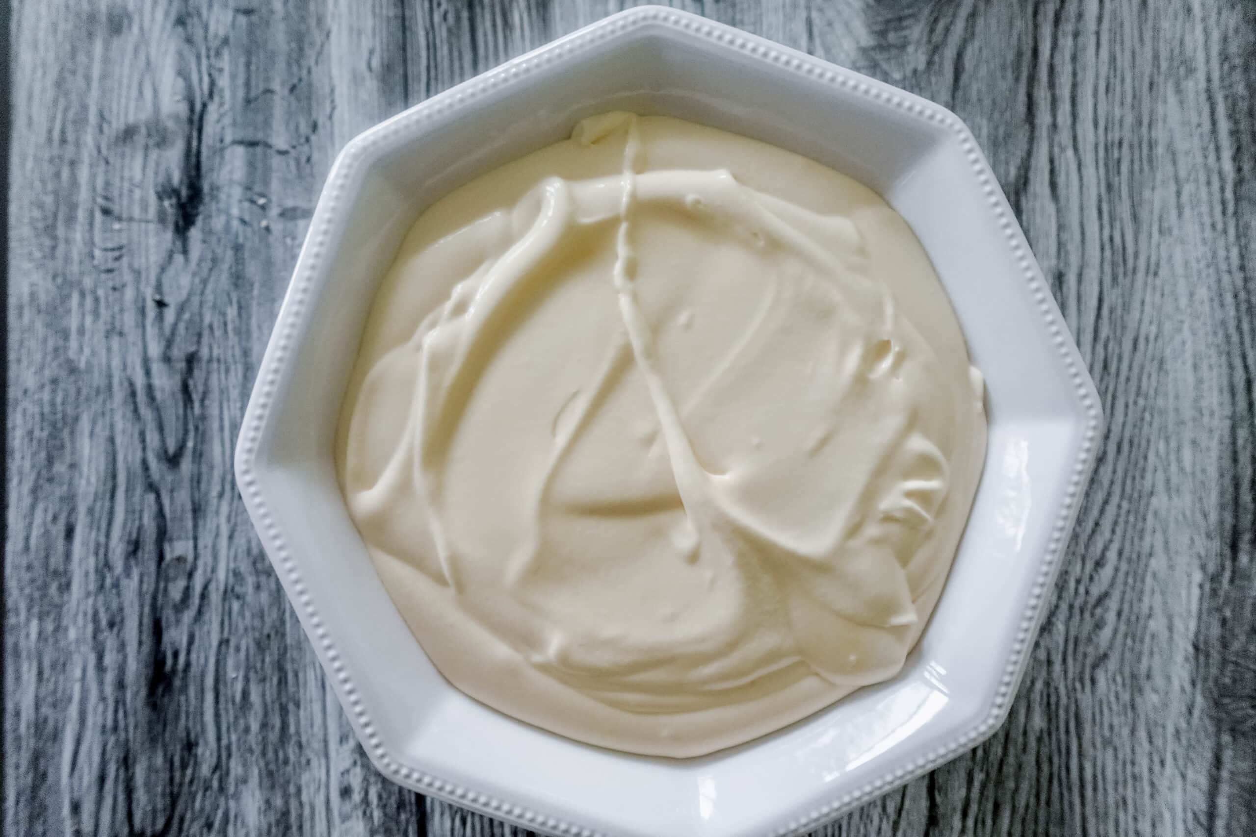Overhead shot of a white octagonal bowl filled with smooth Bavarian cream sits on a gray wooden surface.