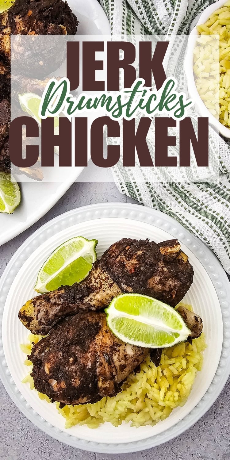 A plate with two jerk chicken drumsticks on a bed of yellow rice, garnished with lime wedges. In the background, more chicken, a striped cloth, and bold text reading Jerk Drumsticks Chicken.