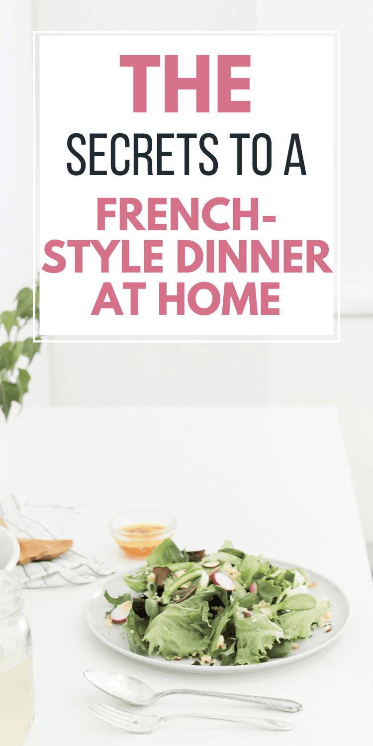 A plate of fresh salad with cutlery on a white table, next to a glass of water and a small dish of dressing. Overlaid text reads The Secrets to a French-Style Dinner at Home.